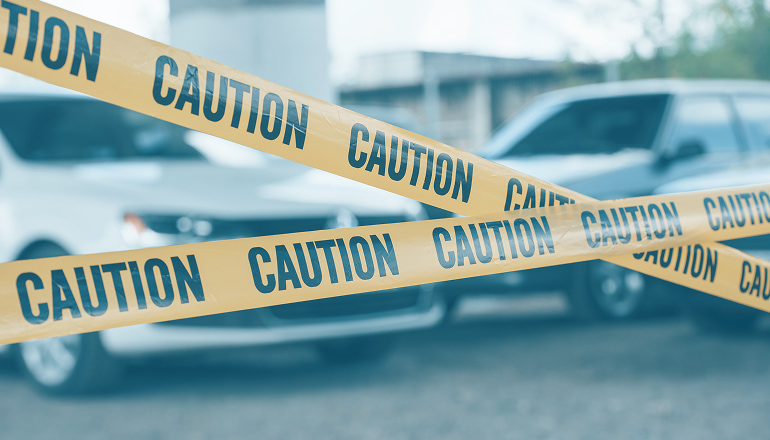 coches detrás de cintas de caution puestas por un forense, a la espera de saber cuanto tarda el forense en emitir el informe del accidente de tráfico